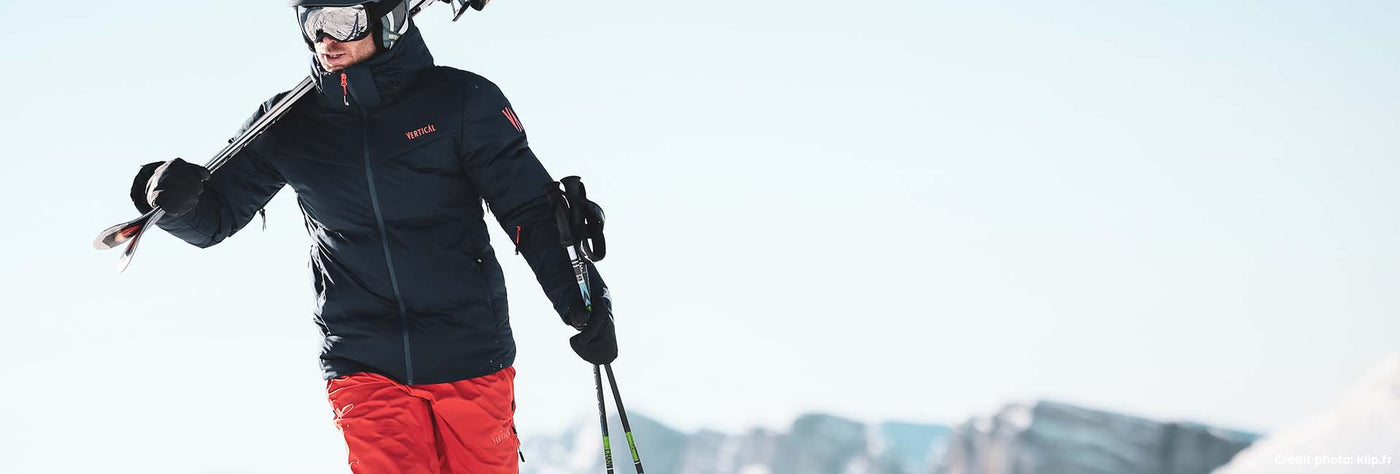 Tenue de ski Vertical, techniques, chaud, imperméable. L'homme pote la doudoune de ski et un pantalon de ski, ainsi qu'un casque de ski